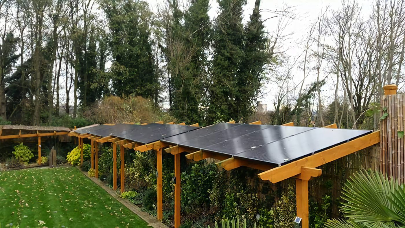 A timber pergola in a garden with solar panels forming its roof